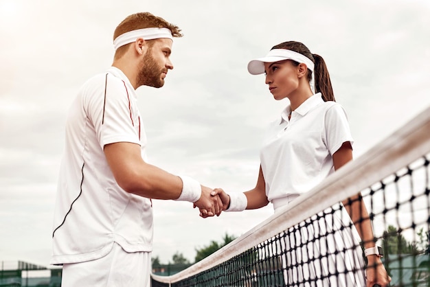 Pareja joven de socios está jugando al tenis