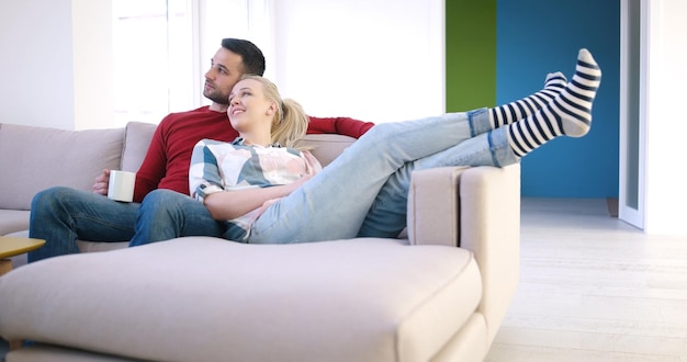 Pareja joven en el sofá viendo la televisión juntos en su casa de lujo