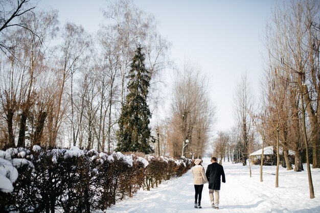 Pareja joven sonríe y besándose en el parque en invierno