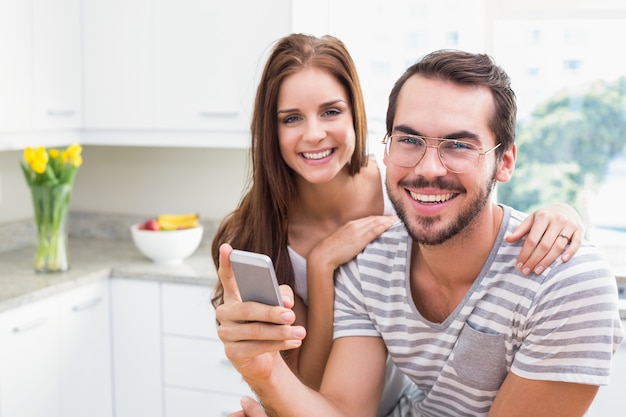 Pareja joven sonriendo a la cámara hombre sosteniendo smartphone