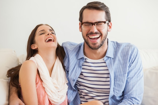 Pareja joven sonriendo a la cámara en el sofá