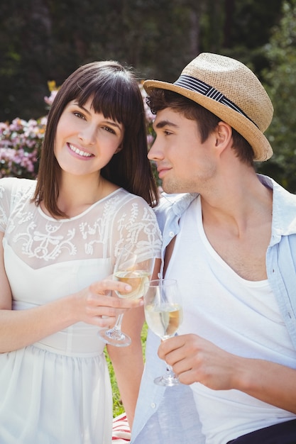 Pareja joven sonriendo y tomando una copa de vino en el jardín