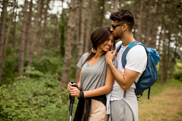 Pareja joven sonriente caminando con mochilas en el bosque en un día de verano