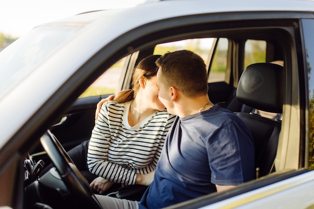 Pareja joven sonriente dentro de un coche. Besos en el coche