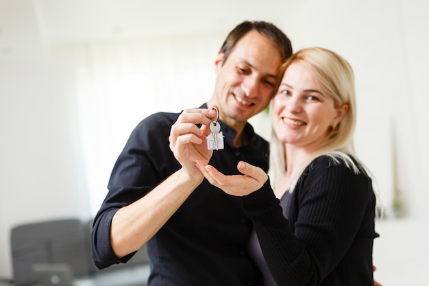 Foto pareja joven sonriente sosteniendo las llaves de su nueva casa