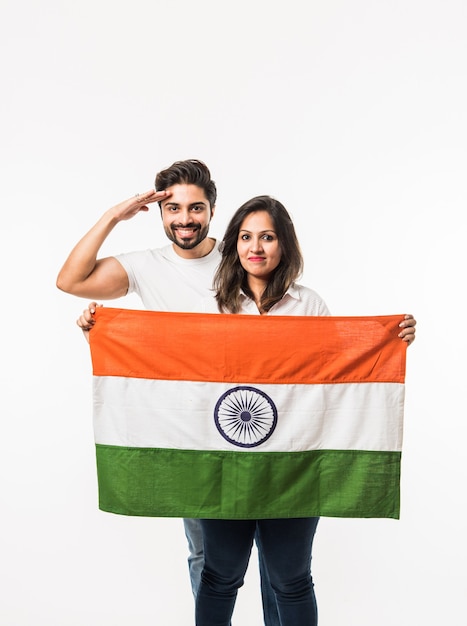 Pareja joven sosteniendo la bandera india en el día de la independencia o la república, que se encuentran aisladas sobre fondo blanco. enfoque selectivo