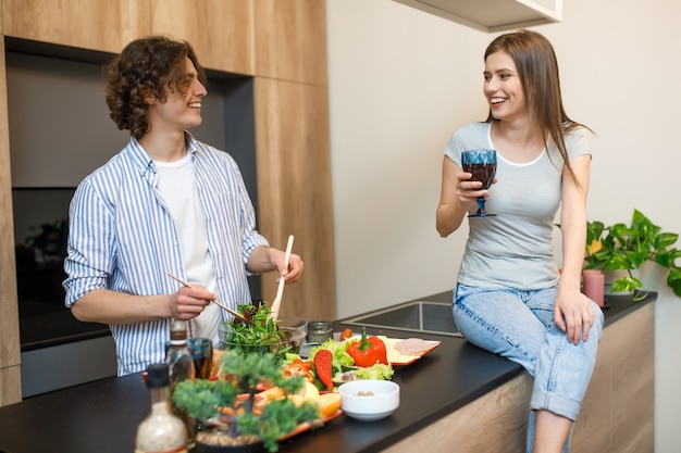 Pareja joven sosteniendo una copa de vino en la cocina de casa