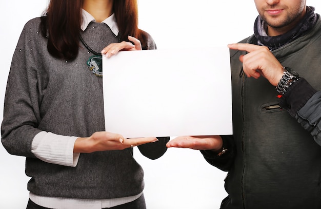 Pareja joven sosteniendo una hoja de papel en blanco