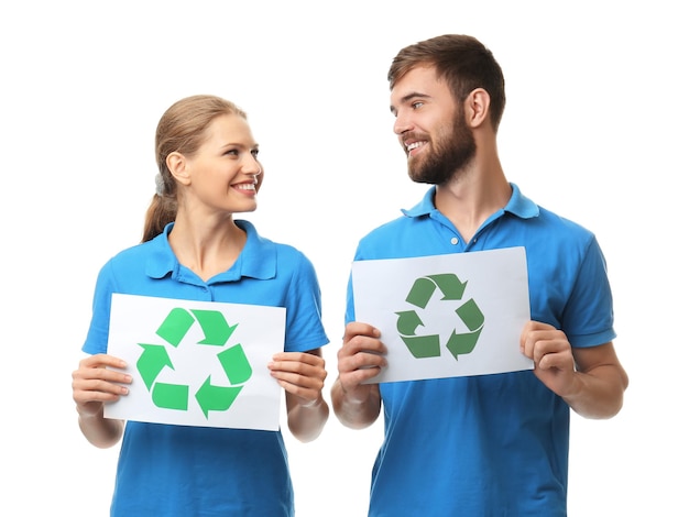Foto pareja joven sosteniendo hojas de papel con símbolo de reciclaje sobre fondo blanco.