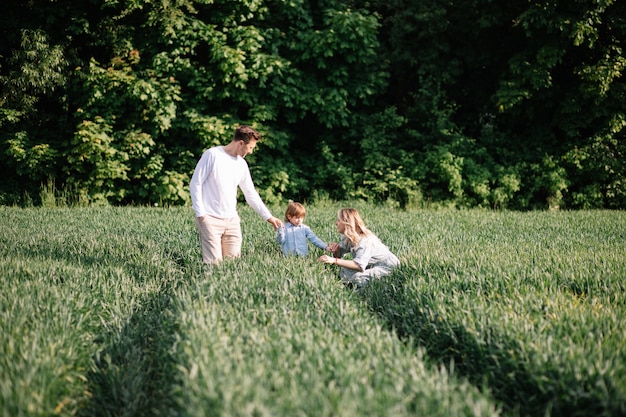 Pareja joven con su hijo haciendo un picnic en la pradera en un día soleado.