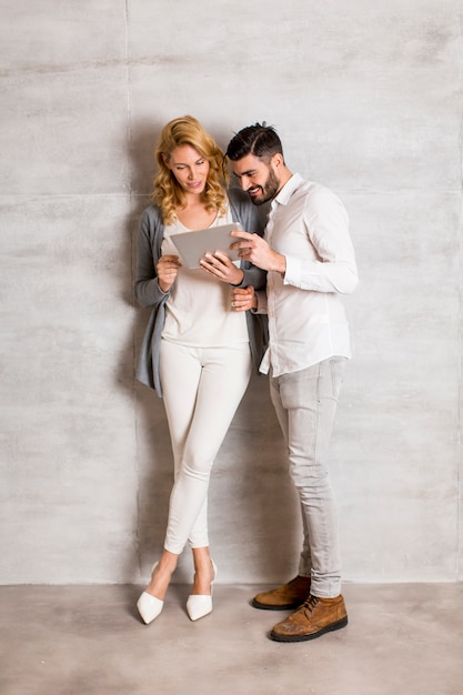 Pareja joven con tableta junto a la pared