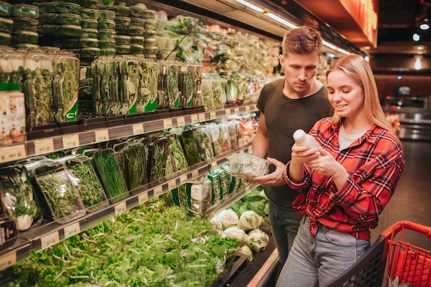 Pareja joven en la tienda de comestibles recogiendo jugo