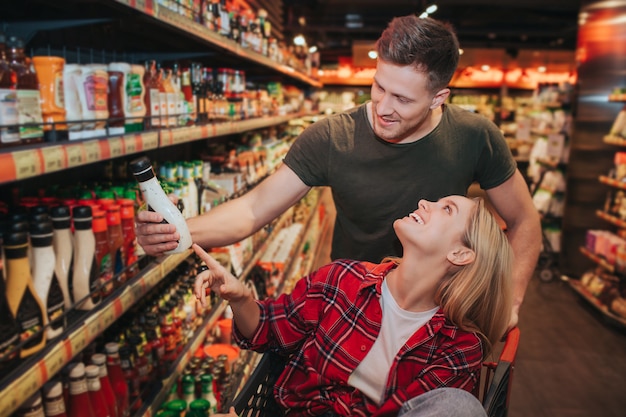 Pareja joven en la tienda de comestibles recogiendo salsa