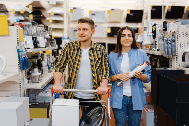 Pareja joven tiene batidora eléctrica en tienda de electrónica. Hombre y mujer comprando electrodomésticos en el mercado