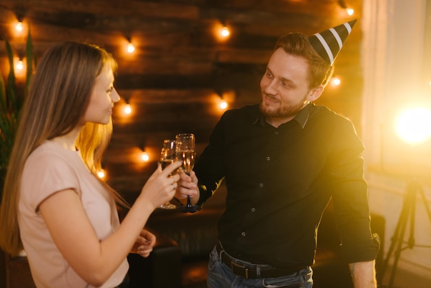 Pareja joven tintineando con copas de champán y celebrando el año nuevo