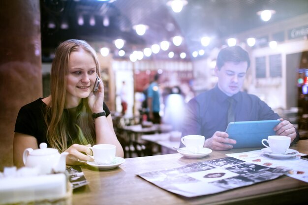 Una pareja joven tomando café en una cafetería vista a través de la ventana