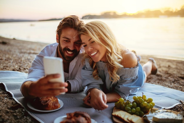 Pareja joven tomando una foto con teléfono móvil en una fecha de picnic