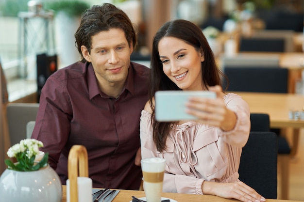 Pareja joven tomando selfie en Cafe