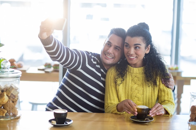 Pareja joven tomando selfie en cafetería