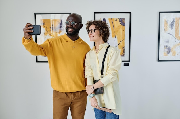 Pareja joven tomando selfie en galería de arte