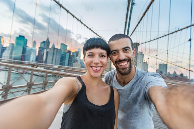 Pareja joven tomando Selfie en el puente de Brooklyn