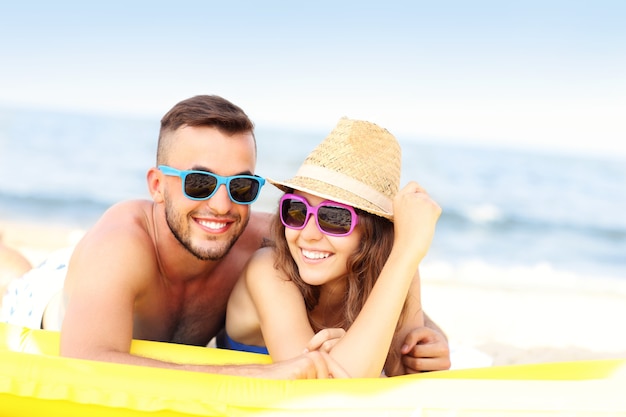 Pareja joven tomando el sol en la playa en un día soleado