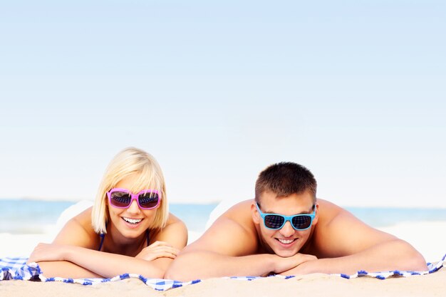 pareja joven tomando el sol en la playa