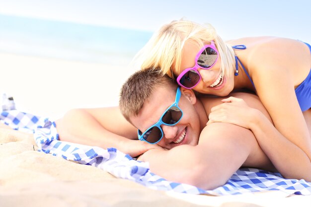 pareja joven tomando el sol en la playa
