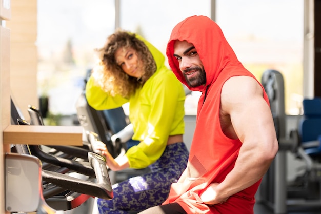 Pareja joven trabajando en el gimnasio haciendo ejercicio en las piernas Bicicleta de entrenamiento cardiovascular