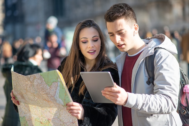 Pareja joven de turistas sosteniendo un mapa en Milán, Italia
