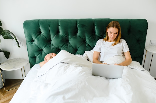 Pareja joven usando laptop juntos en la cama.