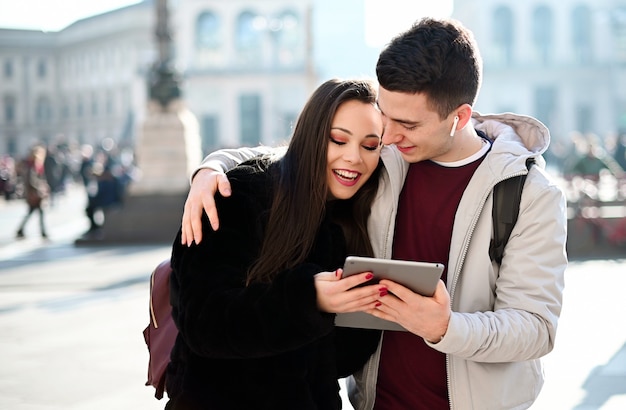 Pareja joven usando una tableta digital al aire libre mientras visitaba una ciudad