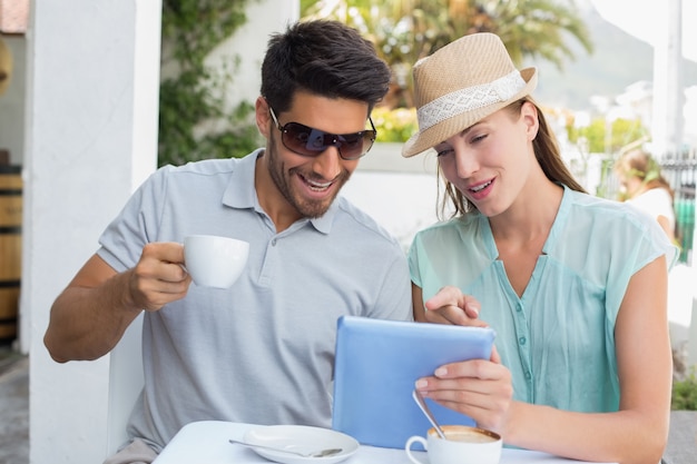 Pareja joven usando tableta digital en la cafetería.