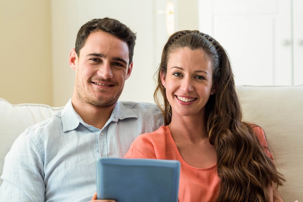 Pareja joven usando tableta digital en el sofá en la sala de estar