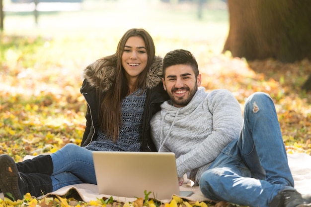 pareja joven, usar la computadora portátil, en, aire libre, en el parque