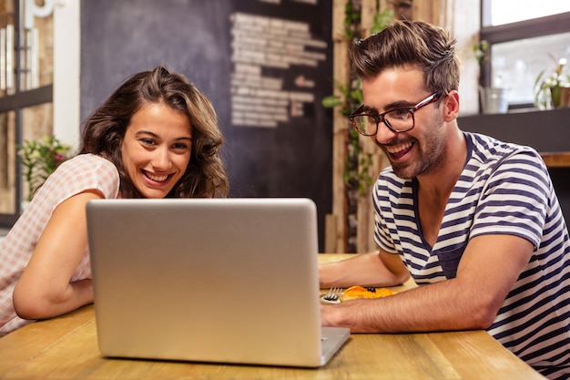 Pareja joven, usar la computadora portátil, en, cafetería