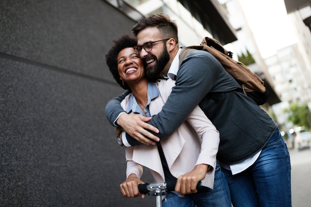 Pareja joven de vacaciones divirtiéndose conduciendo scooter eléctrico por la ciudad.