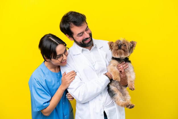 Foto pareja joven veterinario con perro aislado sobre fondo amarillo con expresión feliz