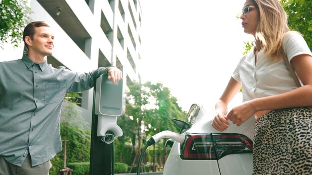 Foto una pareja joven viaja con un coche eléctrico eléctrico en las entrañas de una ciudad sostenible y verde