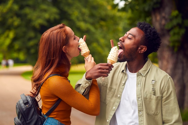 Pareja joven viajando por la ciudad juntos comiendo helados en el parque