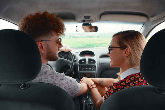 Pareja joven viajando en coche cogidos de la mano