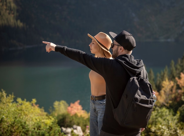 Pareja joven viajando en las montañas. Un hombre está señalando en la montaña con fondo de naturaleza