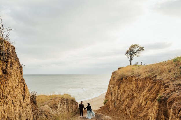 Pareja joven de viajero en el camino al mar con impresionantes vistas de las colinas de arena y agua azul.