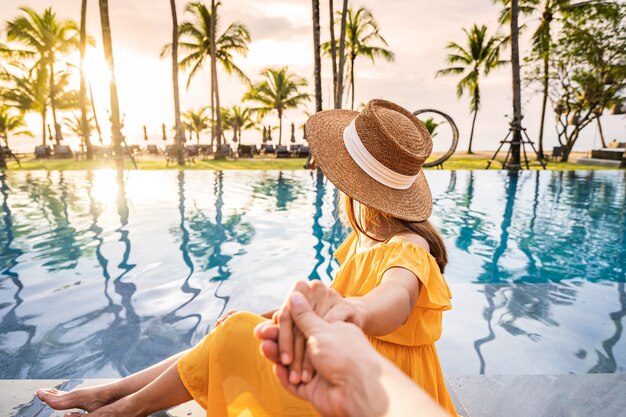 Pareja joven viajero relajarse y disfrutar de la puesta de sol en una piscina tropical mientras viaja