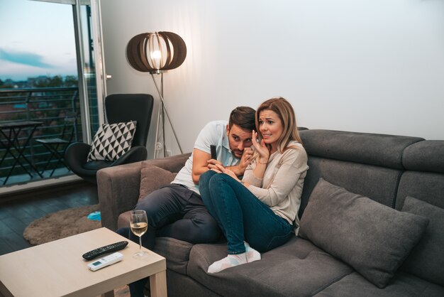 Pareja joven viendo la película de terror en casa.