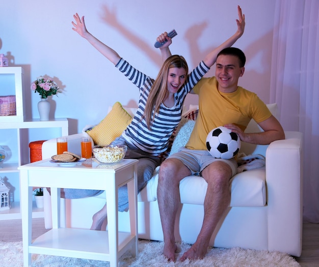 Foto pareja joven viendo la televisión en casa de apagón