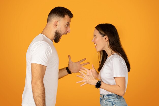 Foto una pareja de jóvenes animados en una animada discusión gestando con las manos ambos con camisetas blancas