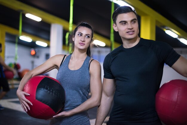 Pareja de jóvenes atletas que se resuelve con pelota médica en el gimnasio de fitness cruz