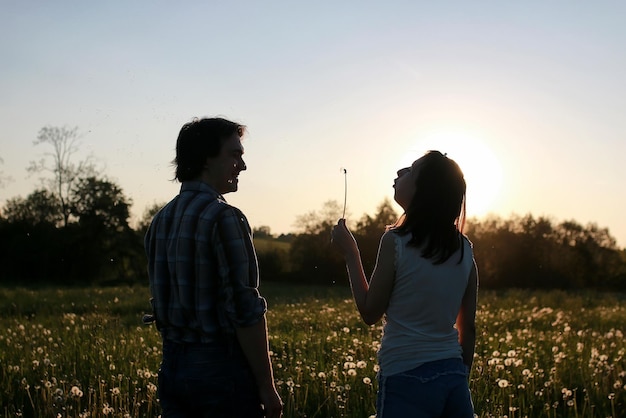 Pareja de jóvenes caminando en la tarde de primavera al atardecer en el campo