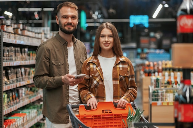 Una pareja de jóvenes están juntos en el supermercado.